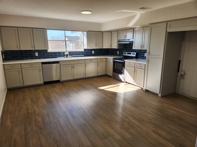 kitchen featuring stainless steel appliances, sink, dark wood-type flooring, and backsplash