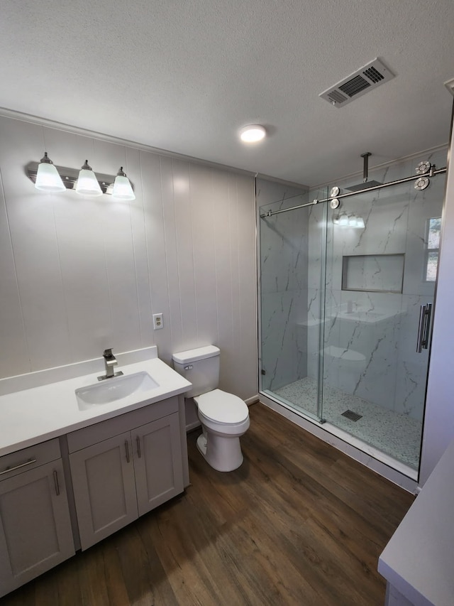 bathroom with toilet, an enclosed shower, wood-type flooring, a textured ceiling, and vanity