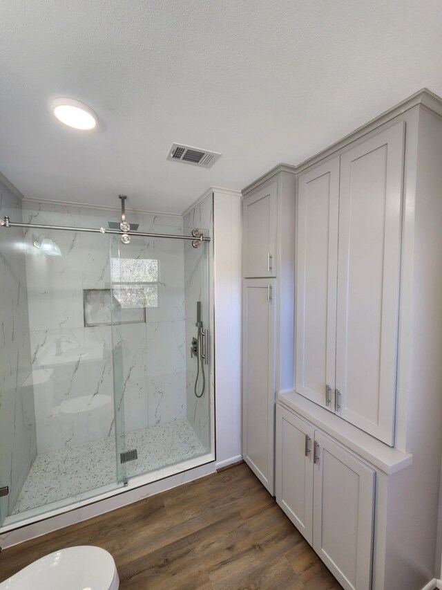 bathroom featuring toilet, an enclosed shower, hardwood / wood-style floors, and a textured ceiling