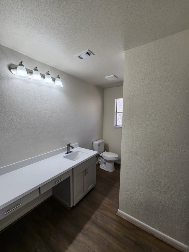 bathroom with hardwood / wood-style flooring, vanity, toilet, and a textured ceiling