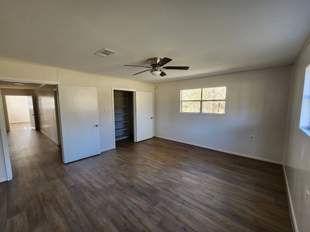 unfurnished bedroom with ceiling fan, dark wood-type flooring, a closet, and a textured ceiling