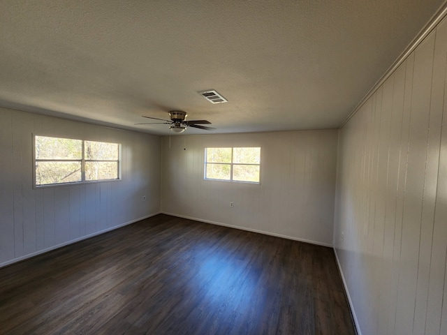 empty room with dark hardwood / wood-style flooring, a textured ceiling, and ceiling fan