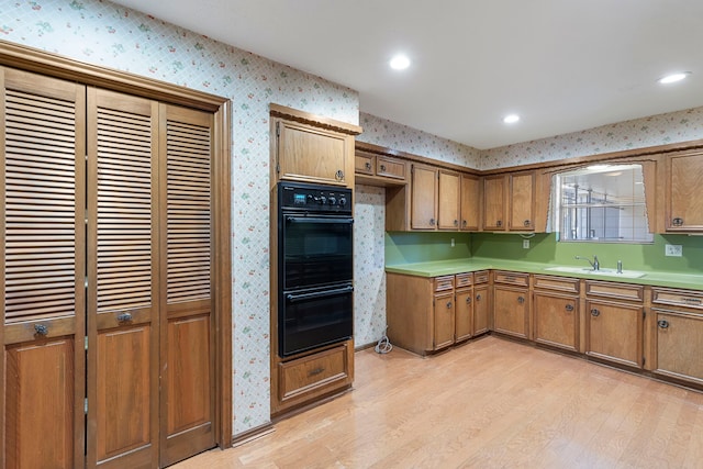 kitchen with double oven, light hardwood / wood-style floors, and sink