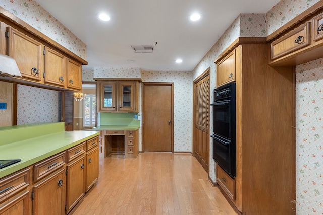 kitchen with a chandelier, double oven, and light hardwood / wood-style floors