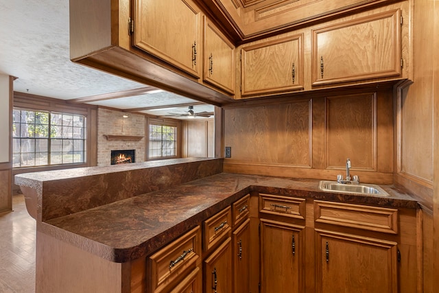 kitchen featuring a brick fireplace, sink, a wealth of natural light, and kitchen peninsula