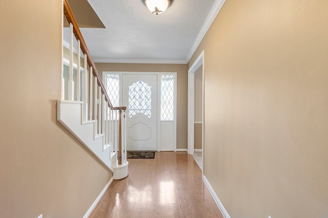 entrance foyer with crown molding, wood-type flooring, and a textured ceiling