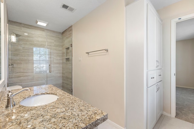 bathroom with tile patterned flooring, vanity, a textured ceiling, and a shower with shower door