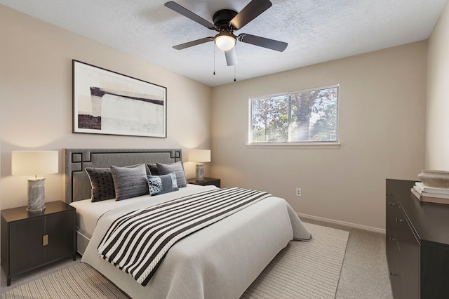 bedroom featuring ceiling fan, light colored carpet, and a textured ceiling