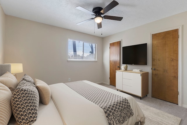 bedroom with ceiling fan, light colored carpet, and a textured ceiling