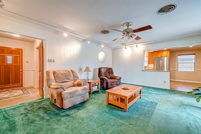 living room with ceiling fan, track lighting, ornamental molding, and carpet floors