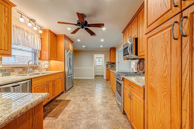 kitchen featuring sink, light stone countertops, a healthy amount of sunlight, and appliances with stainless steel finishes