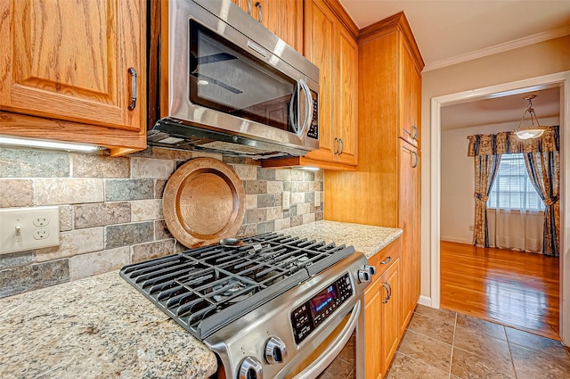 kitchen featuring tasteful backsplash, crown molding, light stone countertops, and appliances with stainless steel finishes