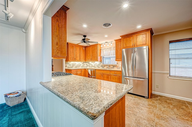 kitchen featuring light stone counters, stainless steel appliances, kitchen peninsula, and decorative backsplash