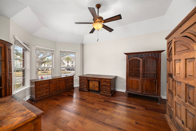 interior space with ceiling fan, a tray ceiling, dark wood-type flooring, and a wealth of natural light