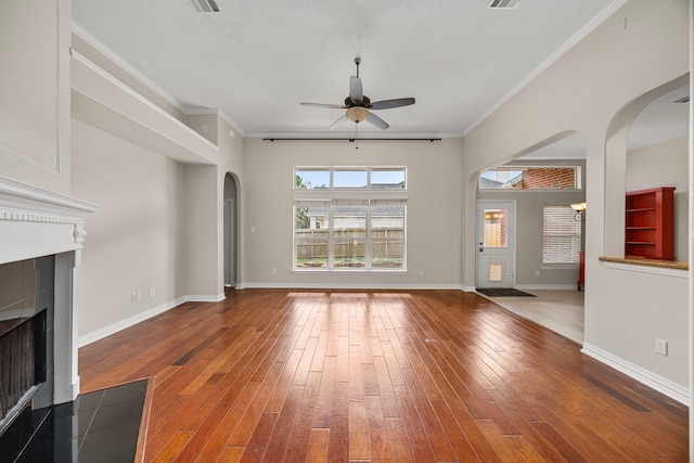 unfurnished living room with ceiling fan, ornamental molding, a fireplace, and hardwood / wood-style floors