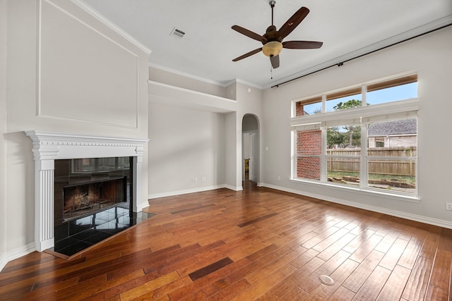 unfurnished living room featuring a tiled fireplace, ornamental molding, hardwood / wood-style flooring, and ceiling fan