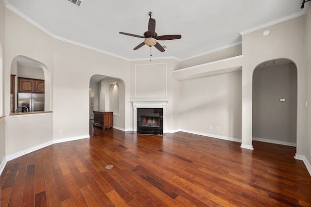 unfurnished living room featuring crown molding, a fireplace, dark hardwood / wood-style floors, and ceiling fan