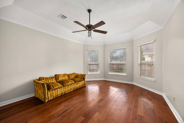 unfurnished room featuring dark hardwood / wood-style floors, ceiling fan, a raised ceiling, crown molding, and a textured ceiling