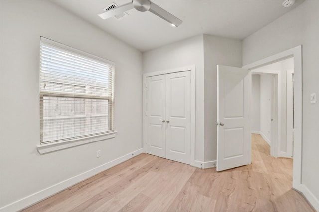 unfurnished bedroom with ceiling fan, a closet, and light wood-type flooring