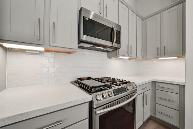 kitchen with stainless steel appliances, gray cabinets, and decorative backsplash