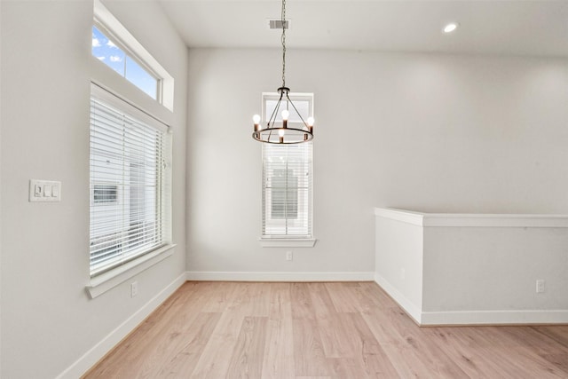 unfurnished dining area featuring a notable chandelier and light wood-type flooring