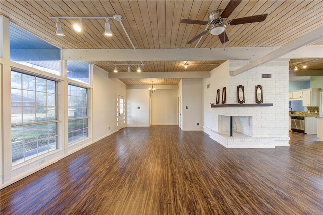 unfurnished living room with a fireplace, beamed ceiling, rail lighting, dark wood-type flooring, and wooden ceiling