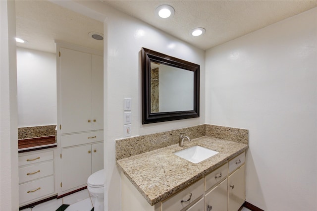 bathroom featuring vanity, a textured ceiling, and toilet