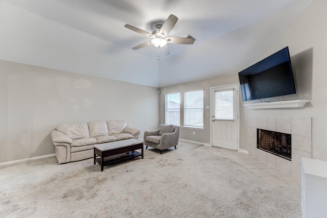 living room with a tile fireplace, lofted ceiling, light carpet, and ceiling fan