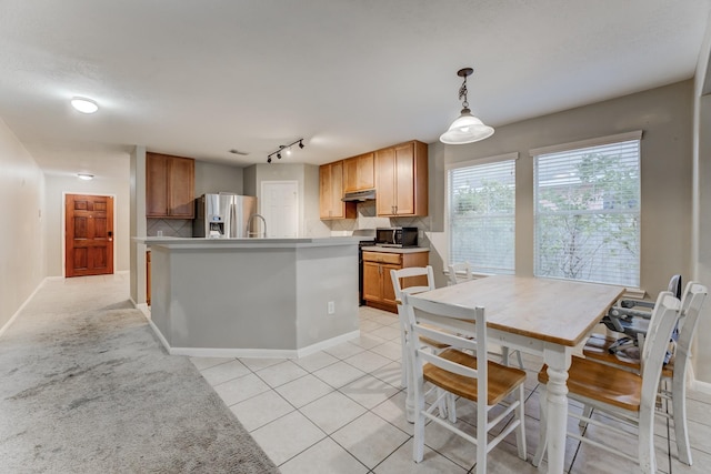 kitchen featuring stainless steel appliances, light tile patterned floors, hanging light fixtures, and backsplash