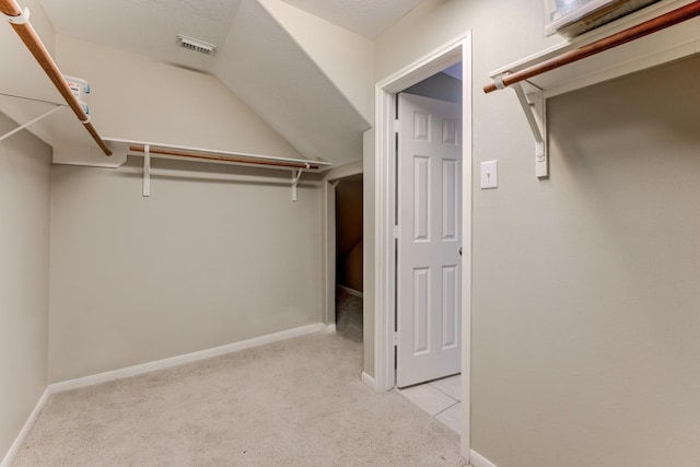 walk in closet featuring lofted ceiling and light carpet