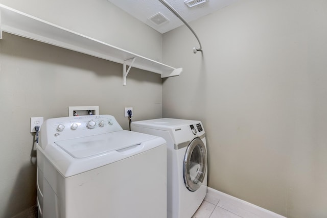 washroom with separate washer and dryer and light tile patterned floors