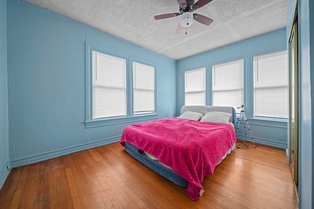 bedroom with wood-type flooring, ceiling fan, and a textured ceiling