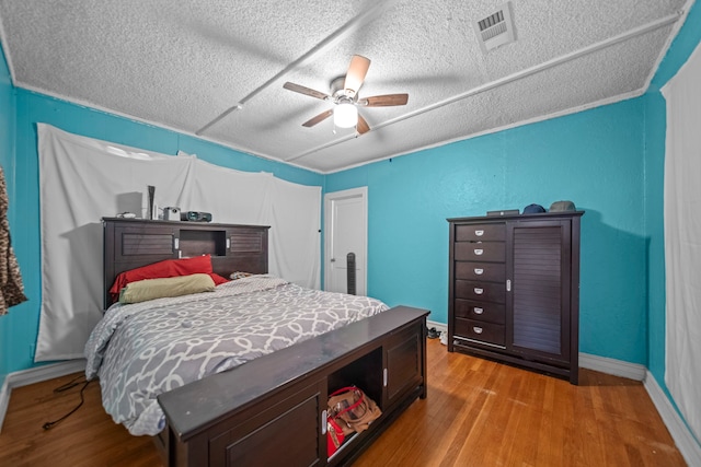 bedroom with ceiling fan, light hardwood / wood-style flooring, and a textured ceiling