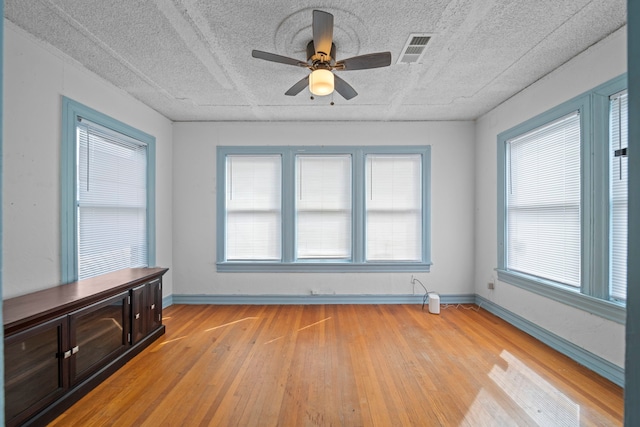 unfurnished sunroom featuring ceiling fan and plenty of natural light