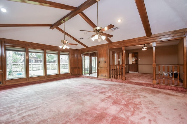 unfurnished living room with high vaulted ceiling, wooden walls, carpet floors, ceiling fan, and beam ceiling