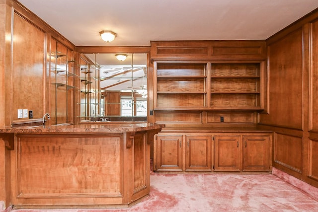 bar with light colored carpet, sink, and wood walls