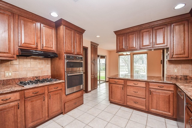 kitchen featuring stainless steel appliances, stone countertops, light tile patterned floors, and backsplash