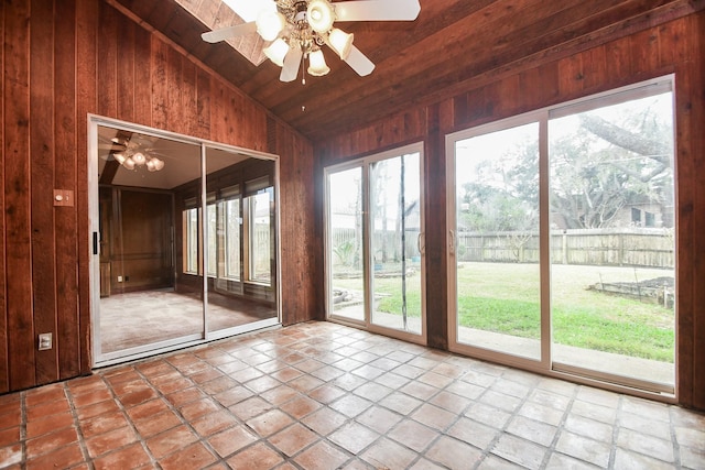 doorway with ceiling fan, lofted ceiling, wood ceiling, and wooden walls