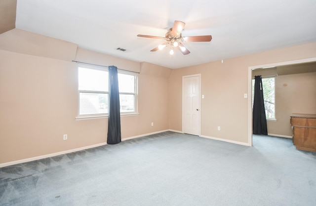 carpeted empty room with a wealth of natural light and ceiling fan