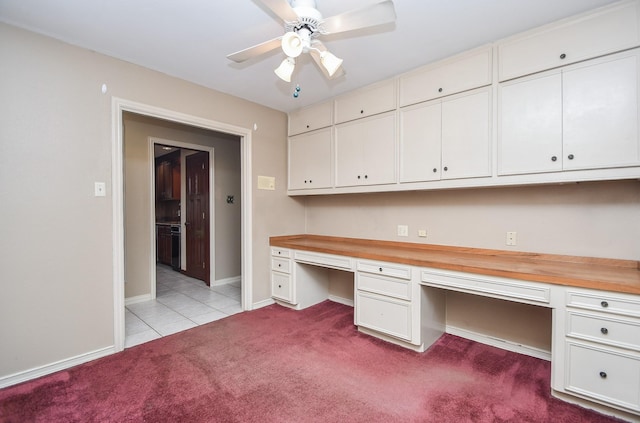 unfurnished office featuring light carpet, built in desk, and ceiling fan