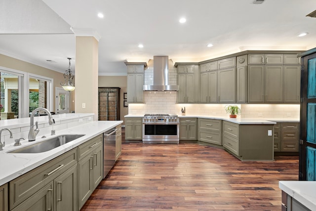 kitchen featuring pendant lighting, appliances with stainless steel finishes, ornamental molding, a sink, and wall chimney exhaust hood