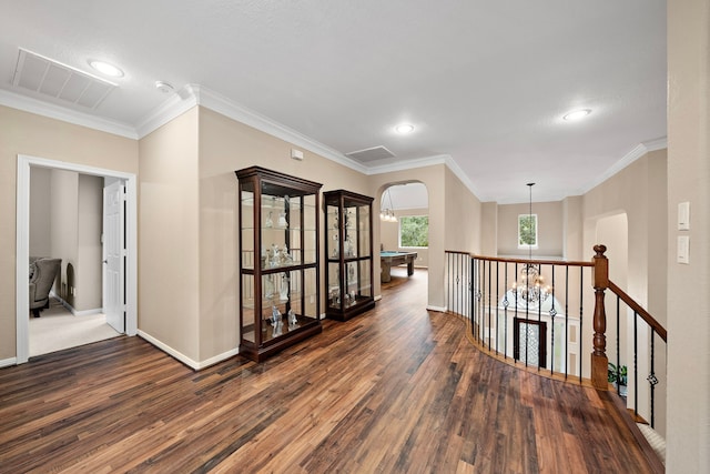 hallway featuring dark wood-style floors, visible vents, arched walkways, and ornamental molding