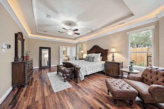 bedroom with baseboards, a tray ceiling, dark wood finished floors, and ornamental molding