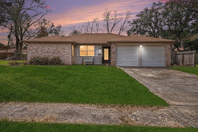 ranch-style house with a garage and a lawn