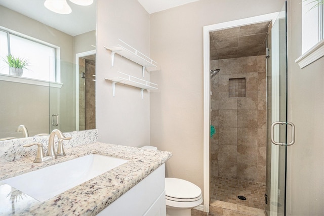 bathroom with a shower with door, vanity, and toilet