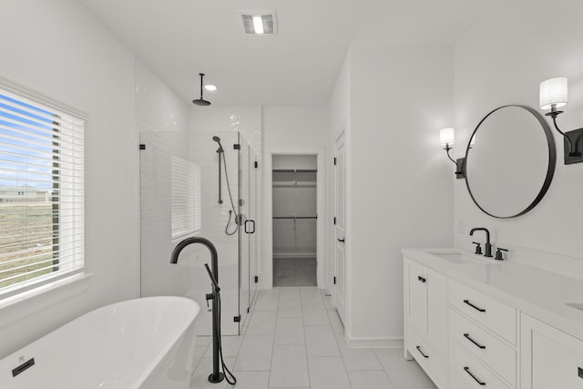 bathroom with a healthy amount of sunlight, plus walk in shower, tile patterned flooring, and vanity