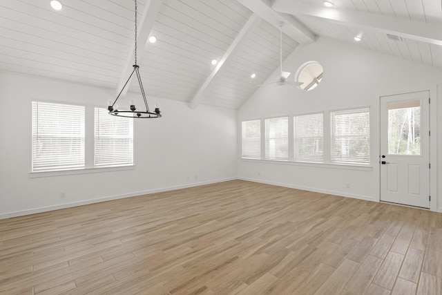 unfurnished dining area featuring beam ceiling, a wealth of natural light, ceiling fan with notable chandelier, and light wood-type flooring