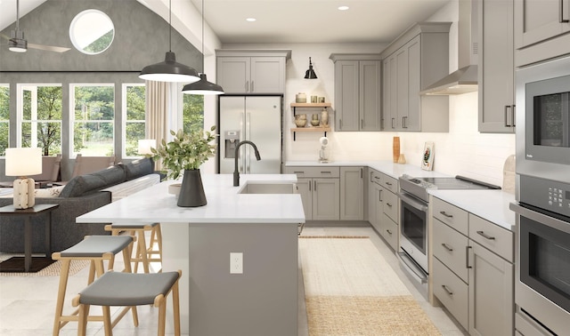 kitchen featuring sink, gray cabinets, a breakfast bar area, appliances with stainless steel finishes, and decorative light fixtures