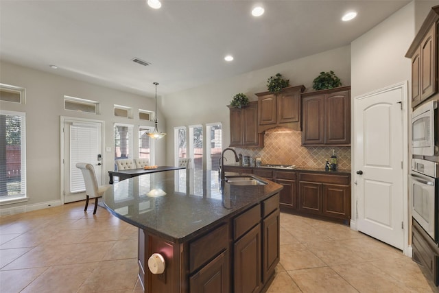 kitchen featuring sink, decorative backsplash, a kitchen island with sink, stainless steel appliances, and dark brown cabinets