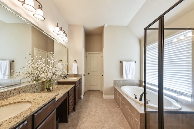 bathroom with plenty of natural light, vanity, lofted ceiling, and tiled tub